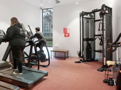 Two people using treadmills in a modern gym at La Trobe University - North and South Apartments.