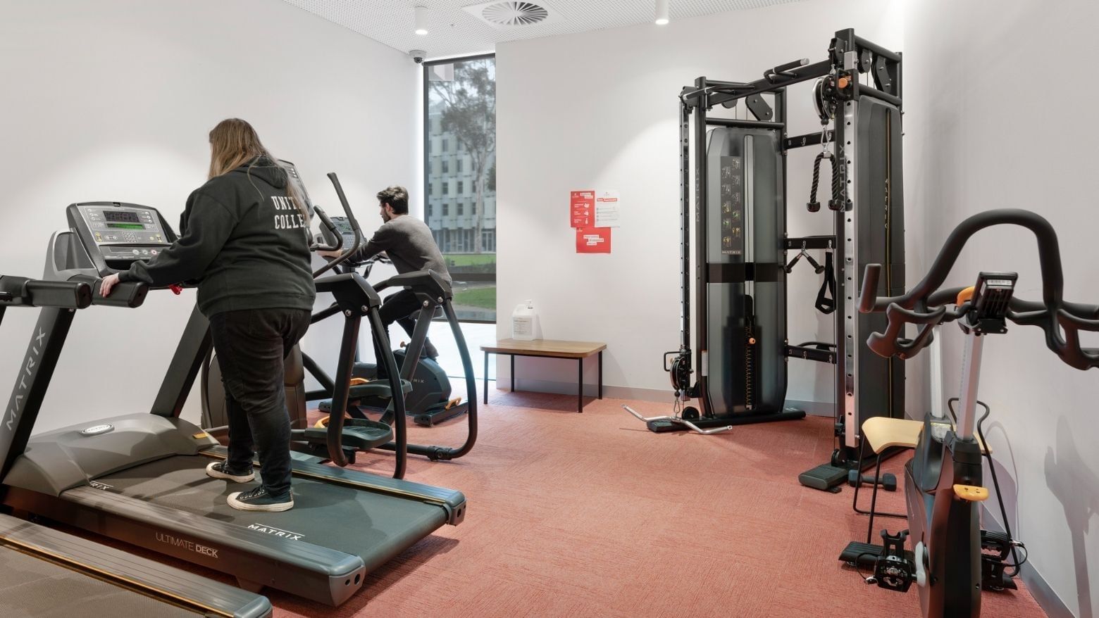 Two people using treadmills in a modern gym at La Trobe University - North and South Apartments.