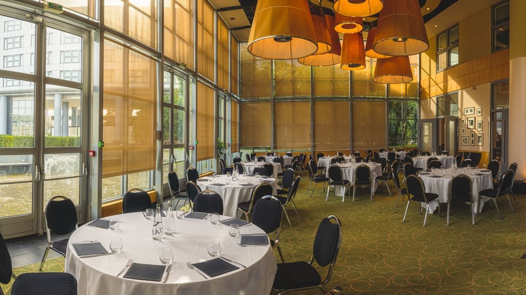 Event room with round tables displaced in a wide space at Atrium Hotel by Penta