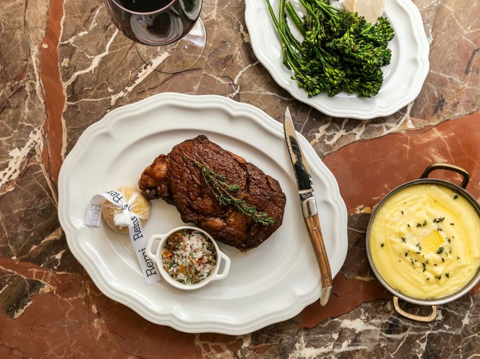 Elegant dining spread with steak, salad, and vegetables at Bar Remi, Uptown Park, Houston restaurants at Granduca Houston