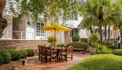 Relaxing outdoor seating area with a yellow umbrella and wooden furniture on the patio at Tradewinds Apartment Hotel