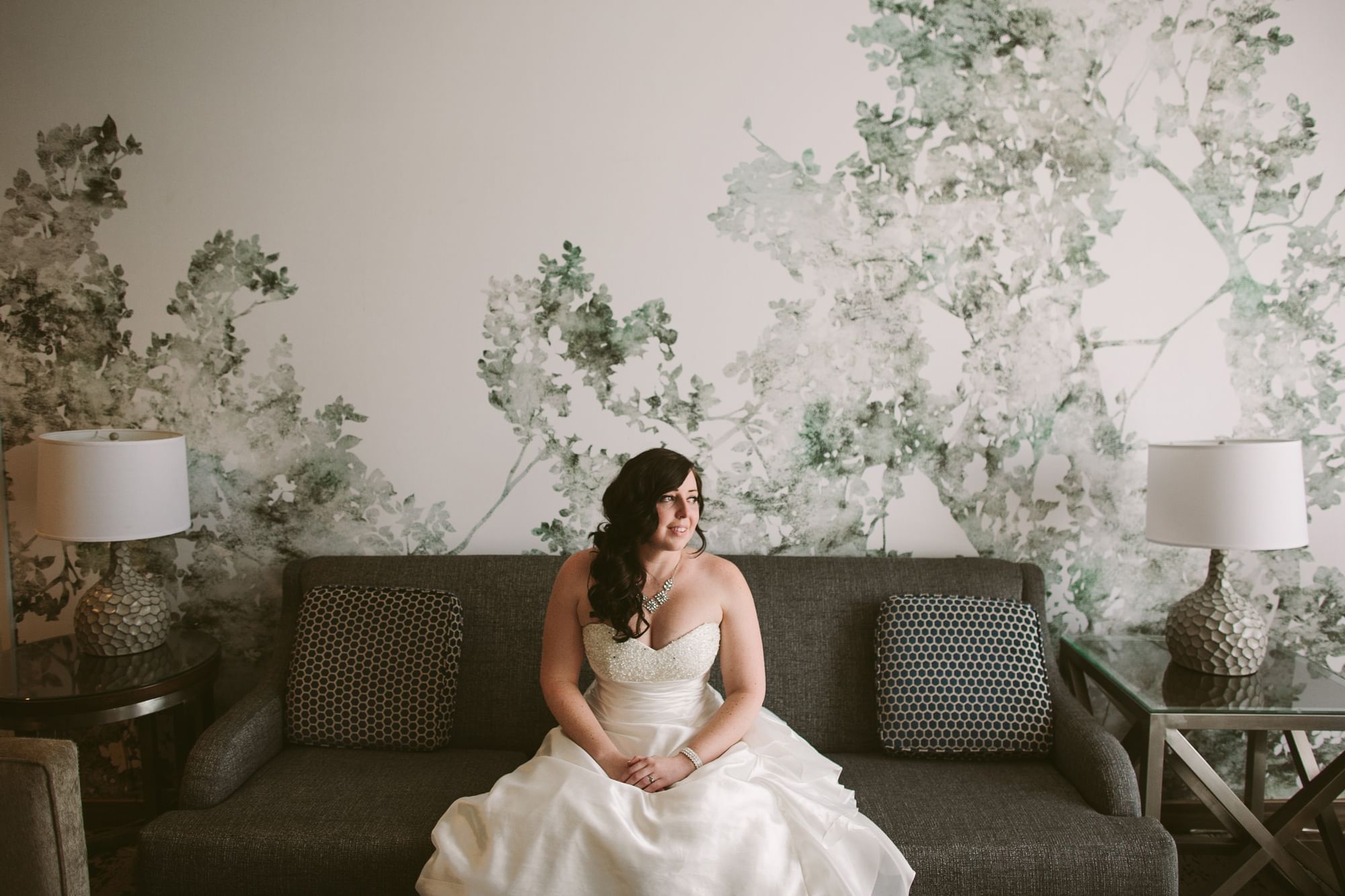 A bride sitting on a couch smiling at Grove Hotel