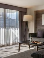 Grey sofa with purple pillows by a coffee table under a floor lamp in Premier Suite at Warwick Denver