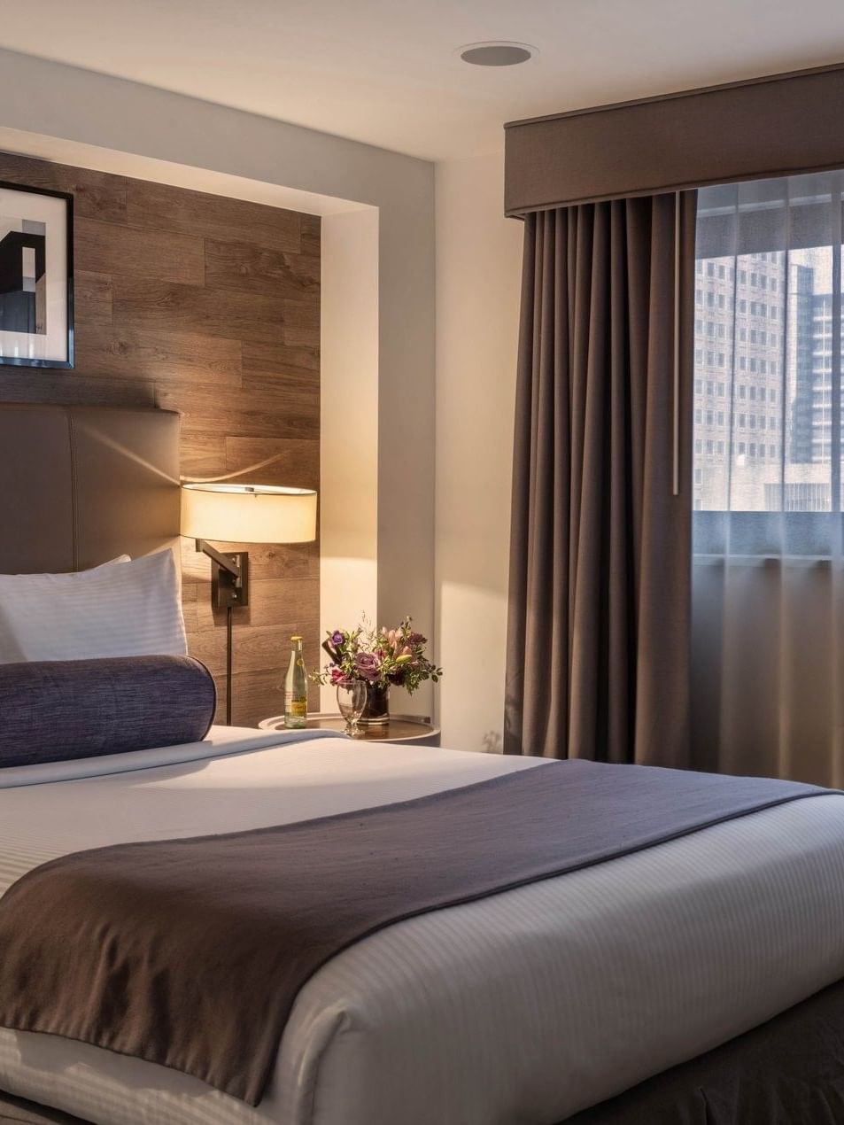 King bed by a side table under a wood-paneled wall in Premier Junior Suites at Warwick Denver