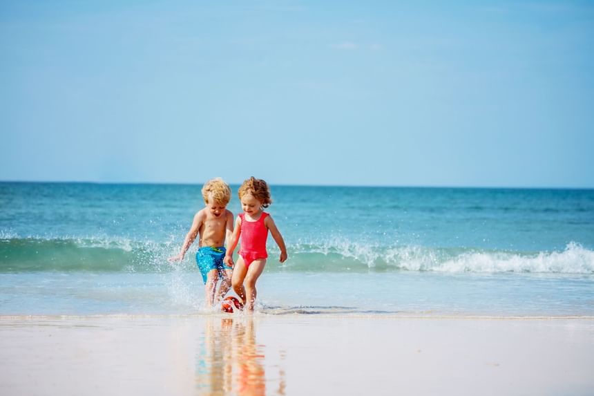 Dos niños jugando con una pelota en la playa en un día soleado cerca de Ponient Hotels