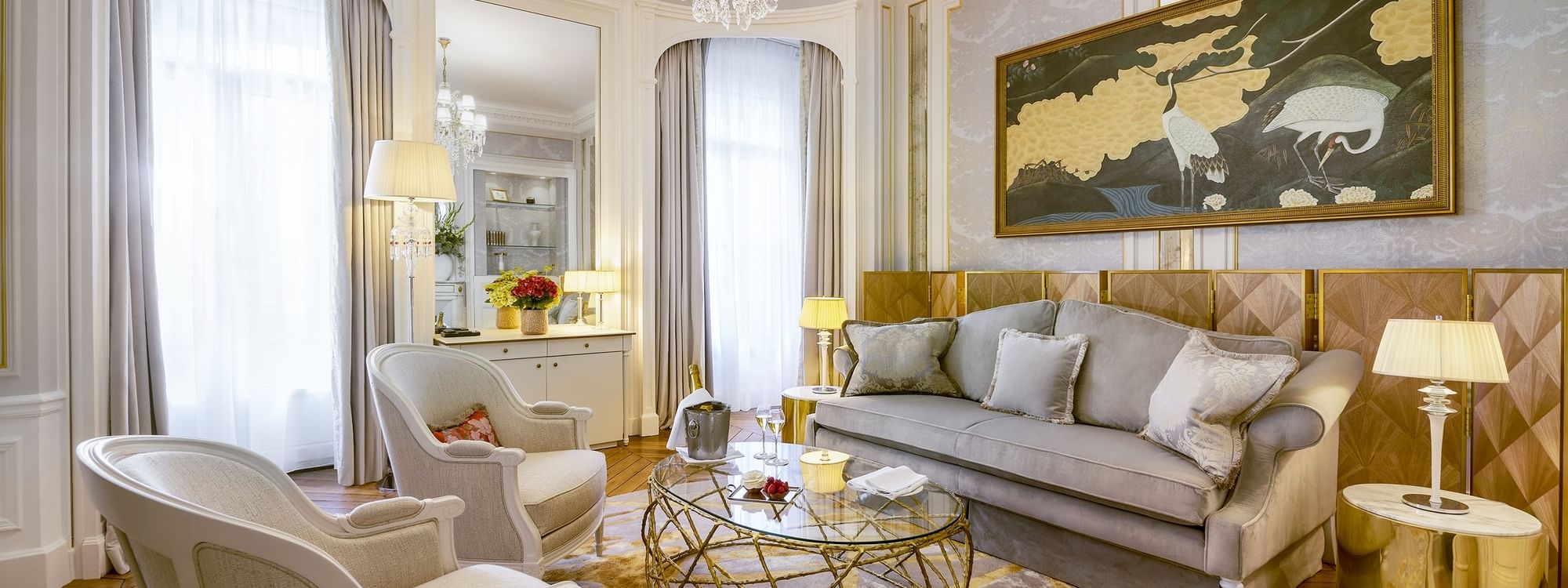 Salon élégant avec canapé, chaises, table basse, lustre, et tableau mural décoratif.