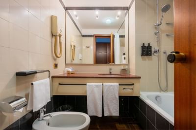 Bathroom vanity, towels, large mirror & bathtub in Classic Room at  Hotel Crivi's in Milan