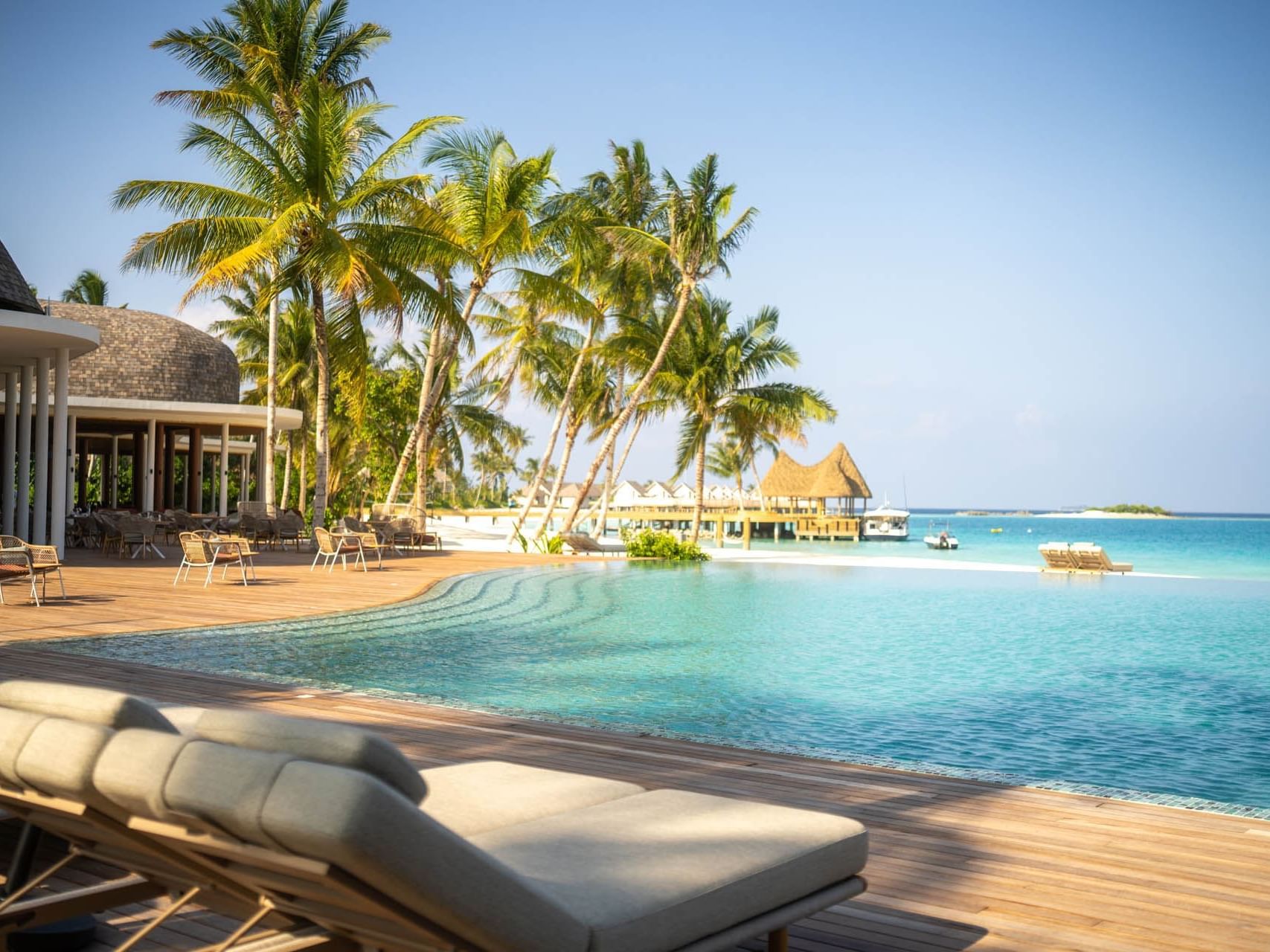 Sunbeds and lounge area by the outdoor swimming pool with a sea view at Ananea Madivaru Maldives