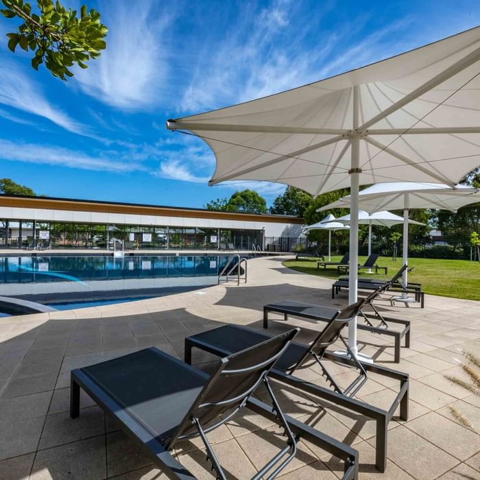 Outdoor pool with sun loungers and white parasols at Mercure Kooindah Waters