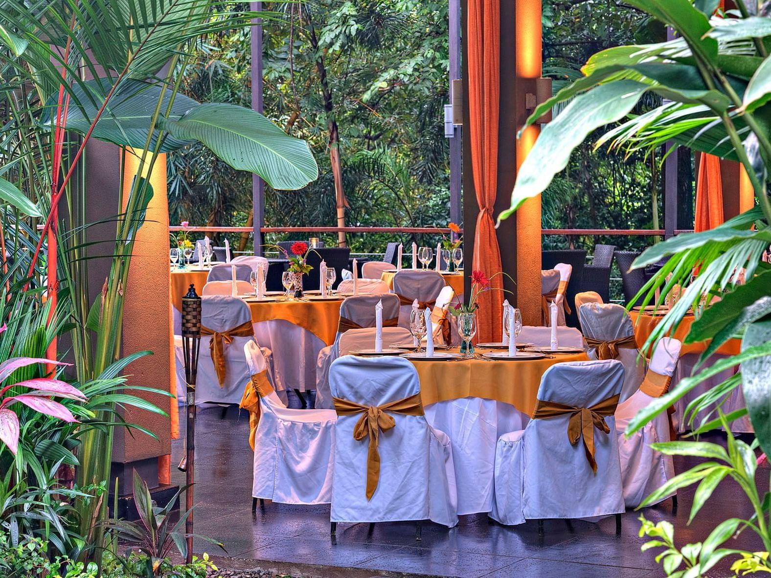 Arreglo de mesa en el restaurante Karola's con exuberante vegetación en Los Altos Resort