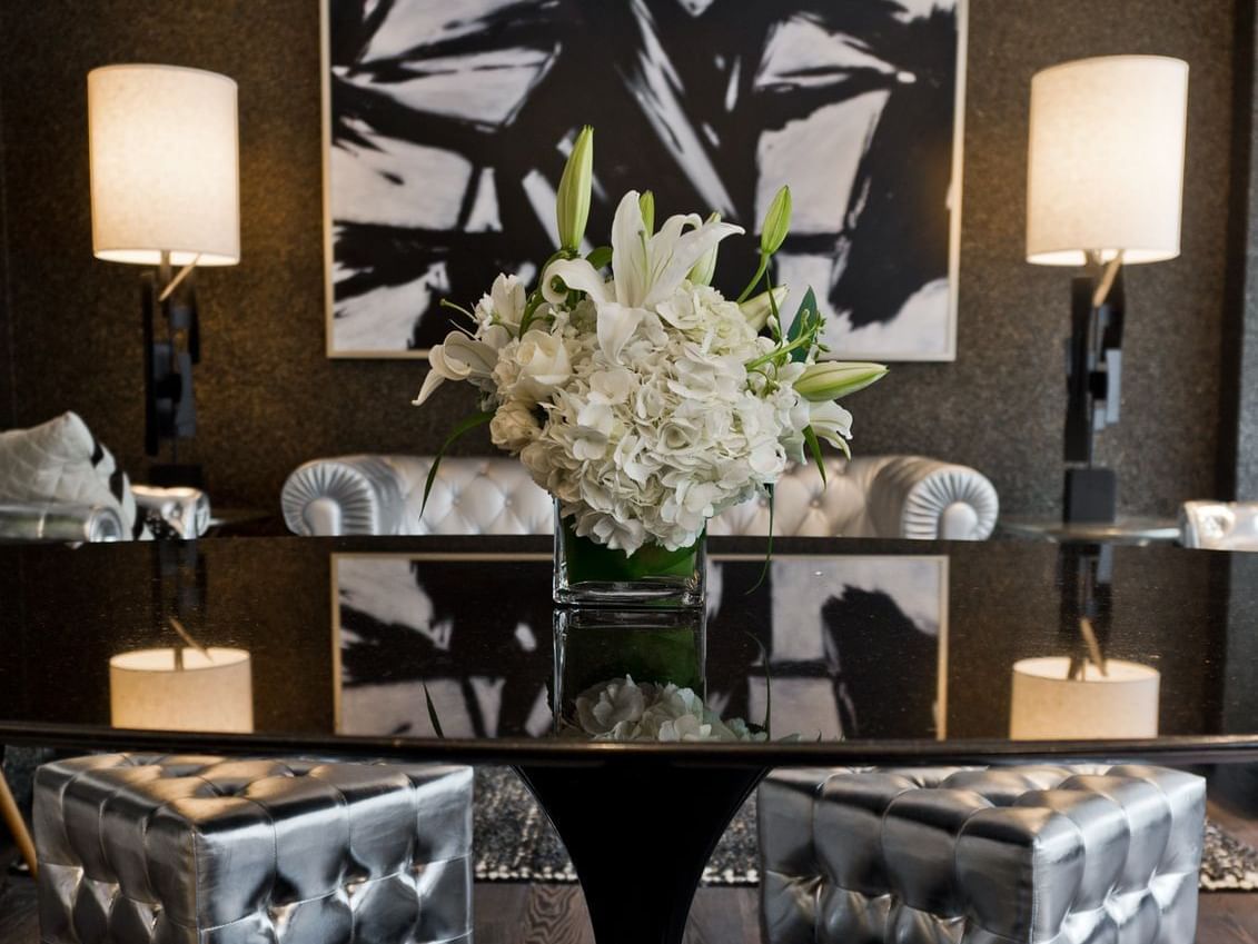 A luxurious lobby with a black table, white flowers, and lamps.