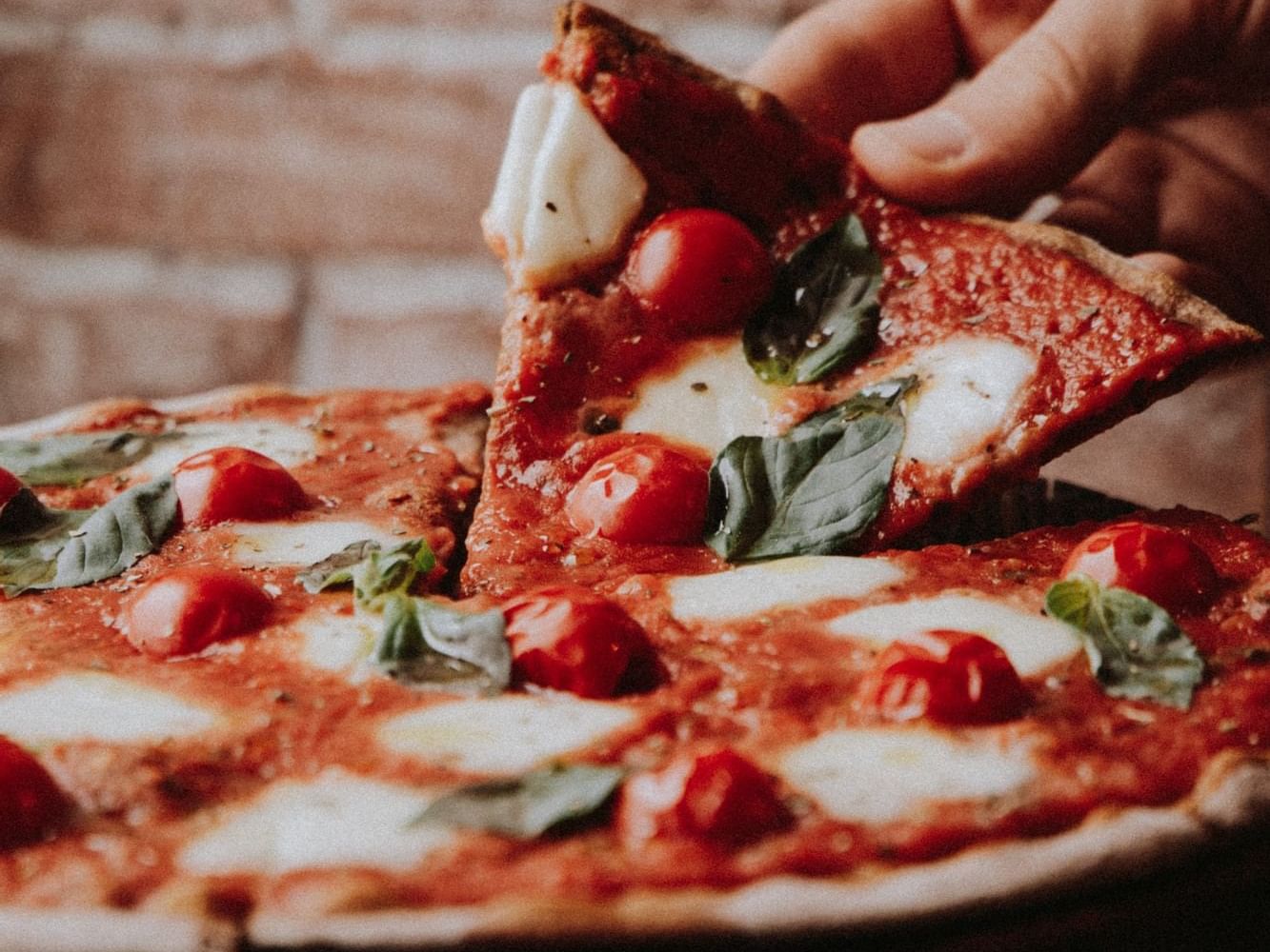 Person picking up a pizza slice