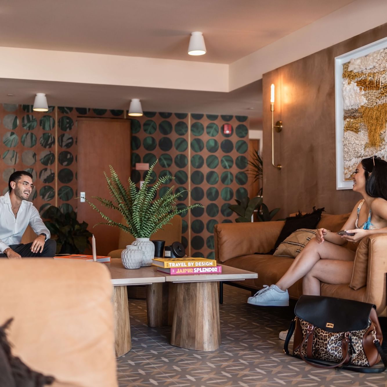 A man and woman chatting in a modern lounge with artwork and plants.