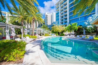 Outdoor pool area with lounge chairs and palm trees, surrounded by The Residences at Seafire
