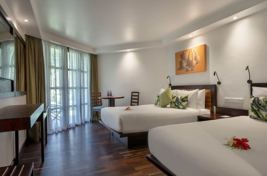 Garden View Rooms feature two beds and a dining table by glass patio doors at Warwick Fiji Resort and Spa