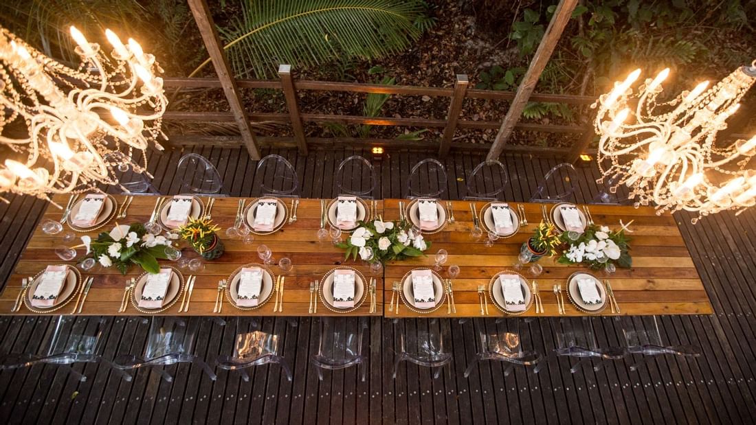 Overhead view of outdoor dining setup with chandeliers, long table & floral centerpieces in Boardwalk at Pullman Port Douglas