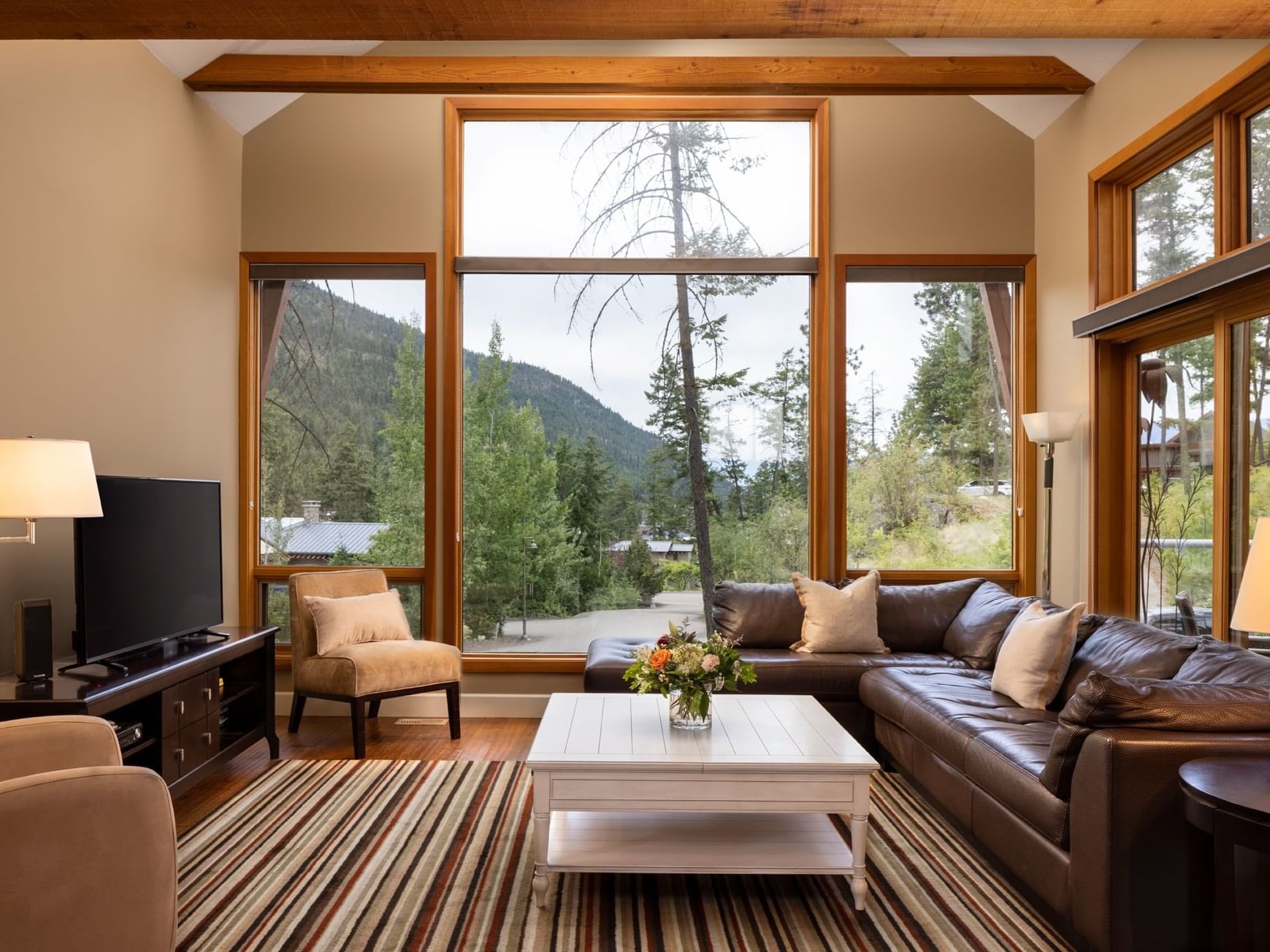 Bright living room with large windows overlooking forest and mountains in Two Bedroom Forest Cabin at Outback Lakeside Vacation Homes