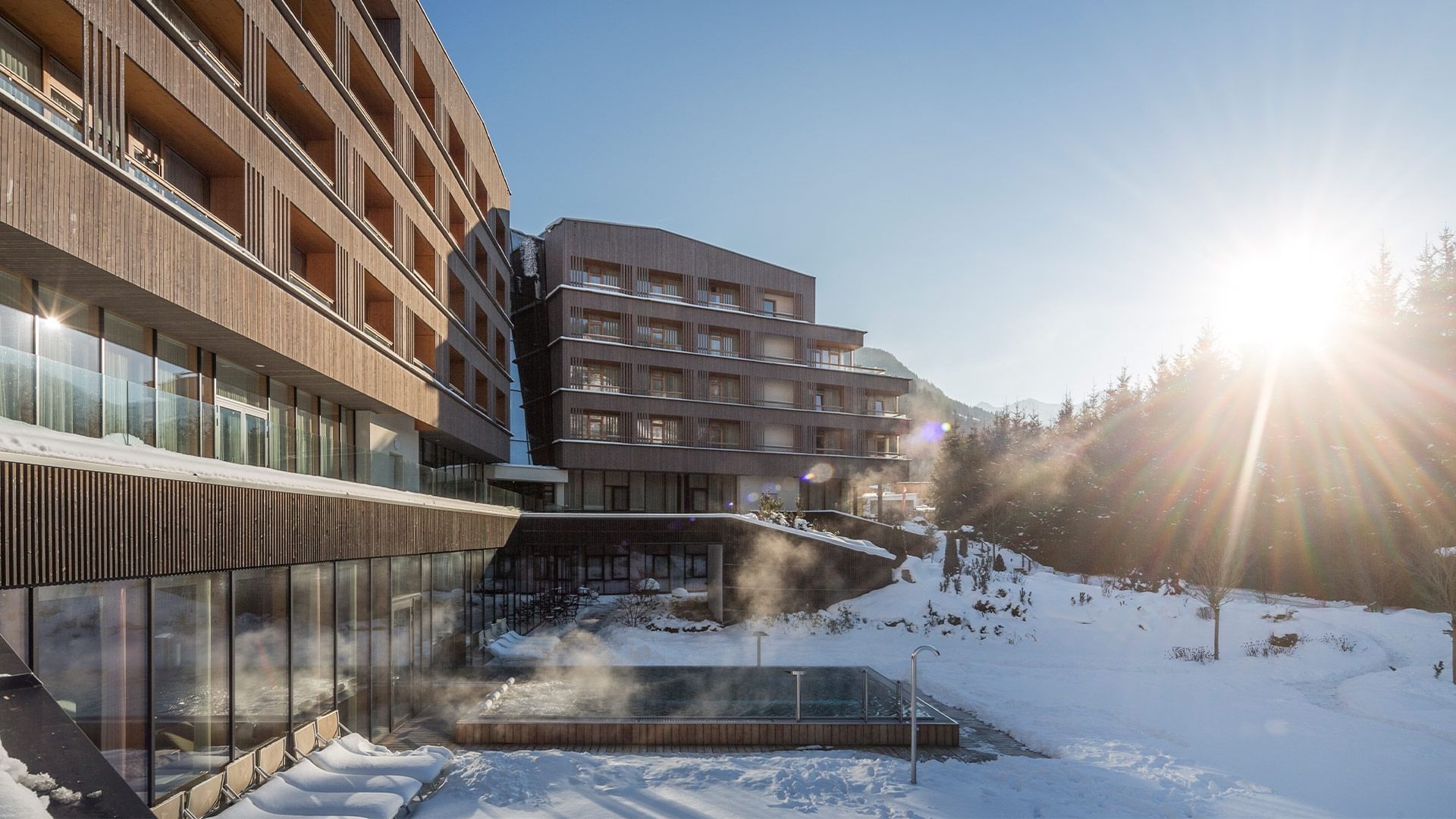 Exterior view of Falkensteiner Hotel Schladming, featuring outdoor pool area in winter