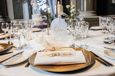 Close-up of elegant wedding table at The Met Hotel Leeds in England, featuring gold plates and a place card