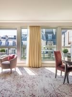 Purple chairs surrounding a dark table by large windows in The Montaigne Suite at Warwick Paris Champs Elysées