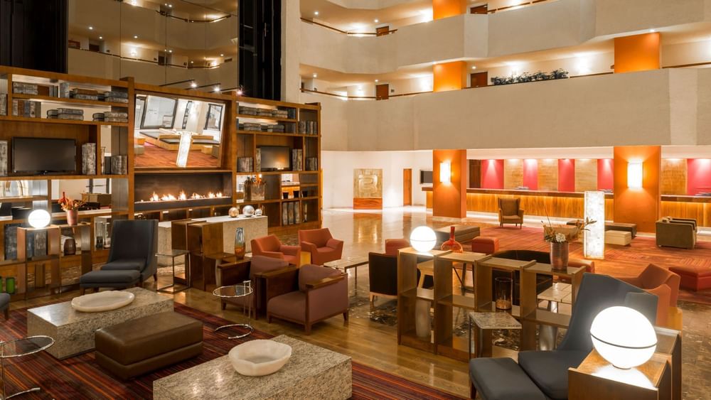 Spacious hotel lobby featuring a fireplace and contemporary seating Camino Real Aeropuerto Mexico