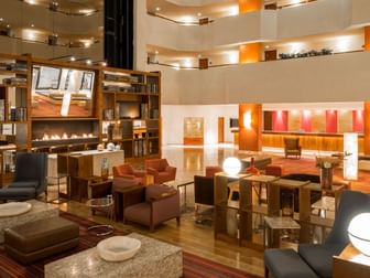 Spacious lounge area featuring plush armchairs and a contemporary fireplace at Camino Real Aeropuerto Mexico