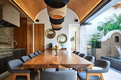 Casa Campanas dining room with a long wooden table under woven pendant lamps at Singular Signature Residences