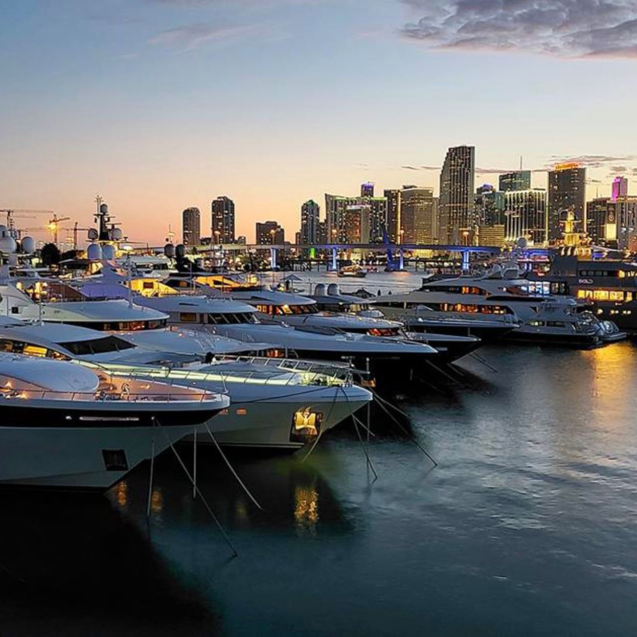 Beautiful dusk view of yachts docked at a marina with the illuminated Miami skyline visible near Tradewinds Apartment Hotel