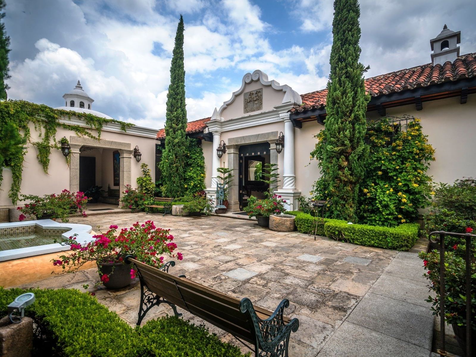Flowers & lush greenery in the garden with a bench at Pensativo House Hotel