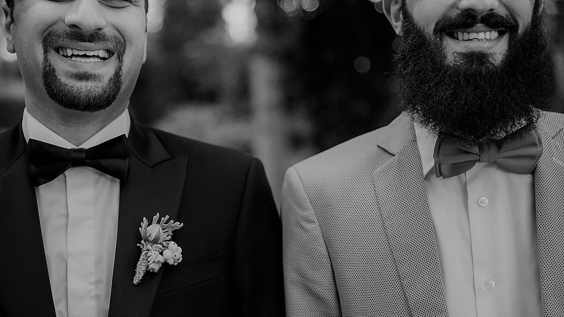 Black-and-white close-up of two grooms smiling on their wedding day at The Sebel Mandurah