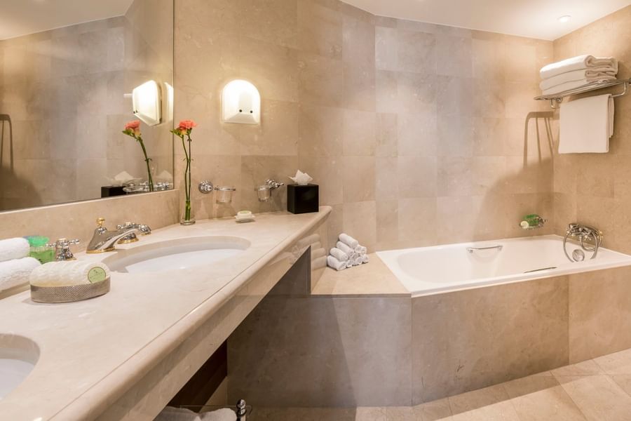 Luxe badkamer met dubbele wastafel en grote badkuip bij Warwick Grand-Place Brussels.
