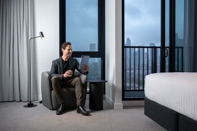 Man on his tablet lounging on a couch at Nesuto Docklands