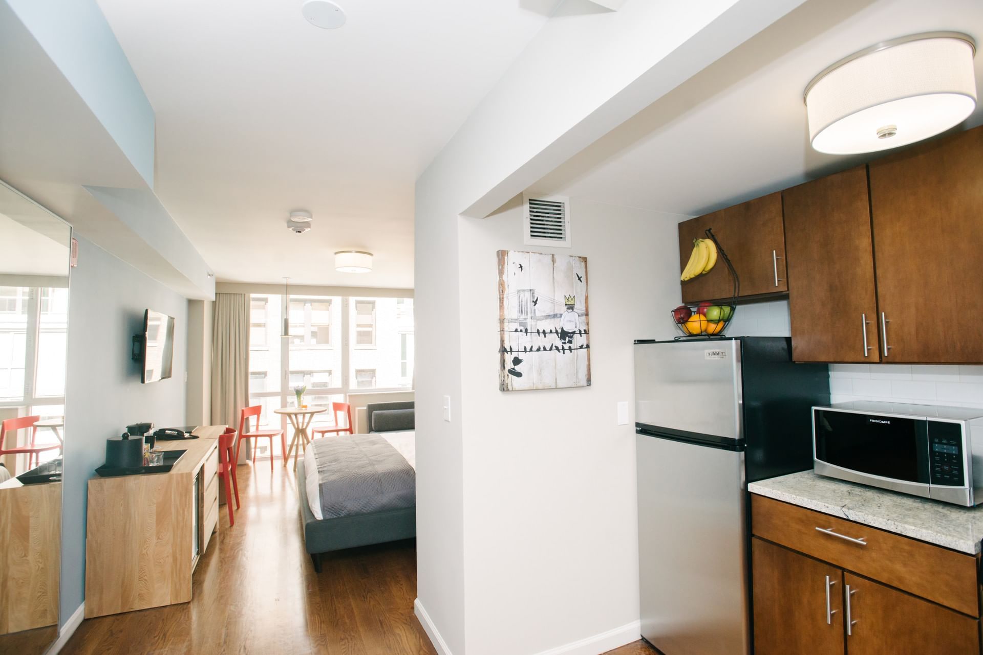 A hotel room with a kitchenette, bed, and sitting area.