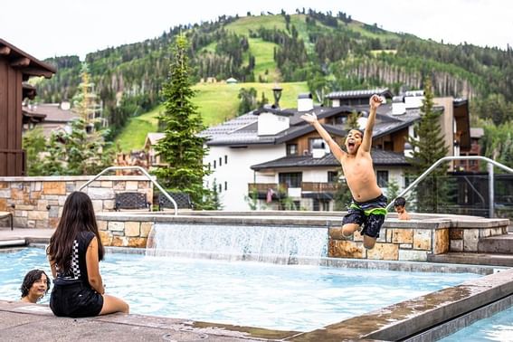A boy jumping in to the outdoor pool at The Chateaux Deer Valley