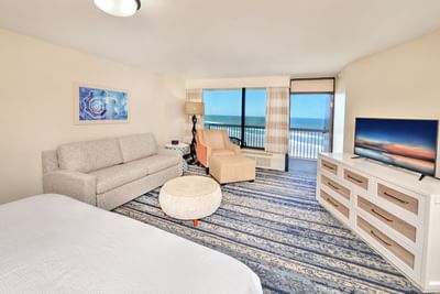 Deluxe Ocean Front Kitchenette room with a couch, chair, TV, and ocean view at the Daytona Bahama House