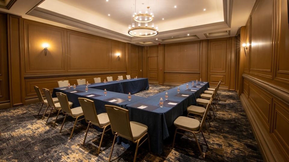 Salon Marques with a U-shaped table, blue linens, and wood-paneled walls at Quinta Real Monterrey