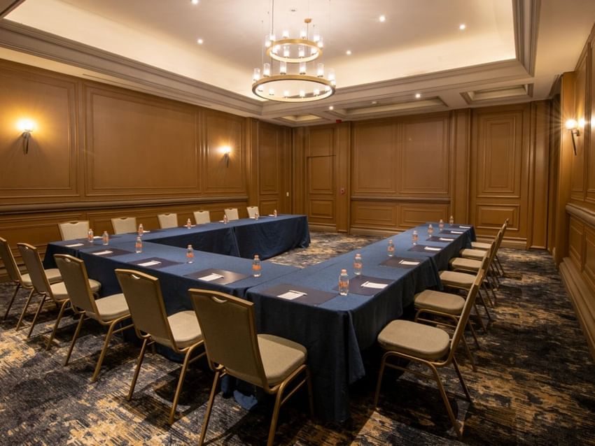 Salon Marques U-shape meeting setup with blue linens, wood paneling, and tiered lighting at Quinta Real Monterrey