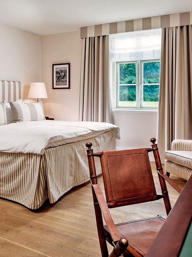 Superior room featuring striped bedding and curtains with leather chair and desk at Warwick Denmark