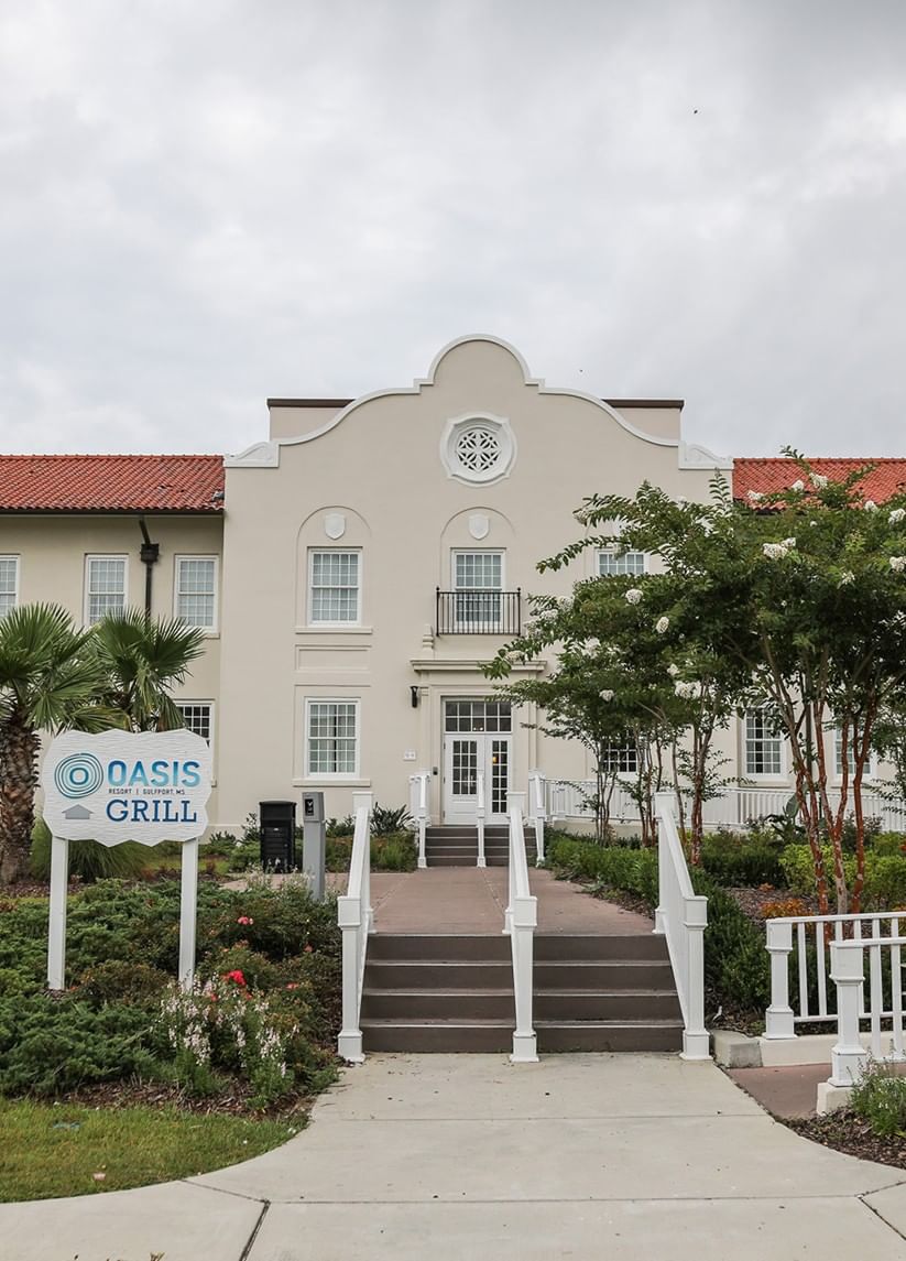 Grand facade of the historical building entrance with an Oasis Grill sign, inviting guests into the Centennial Plaza Resort