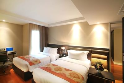 Twin bed & working desk in a room at Amora Hotel