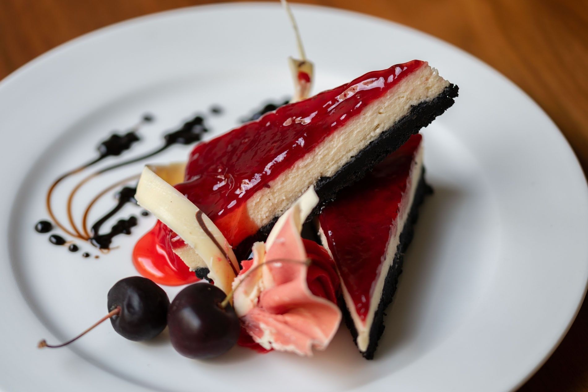 Two slices of cheesecake with a red glaze and dark crust served in the Artist Lobby Lounge at Warwick Hotel Jeddah