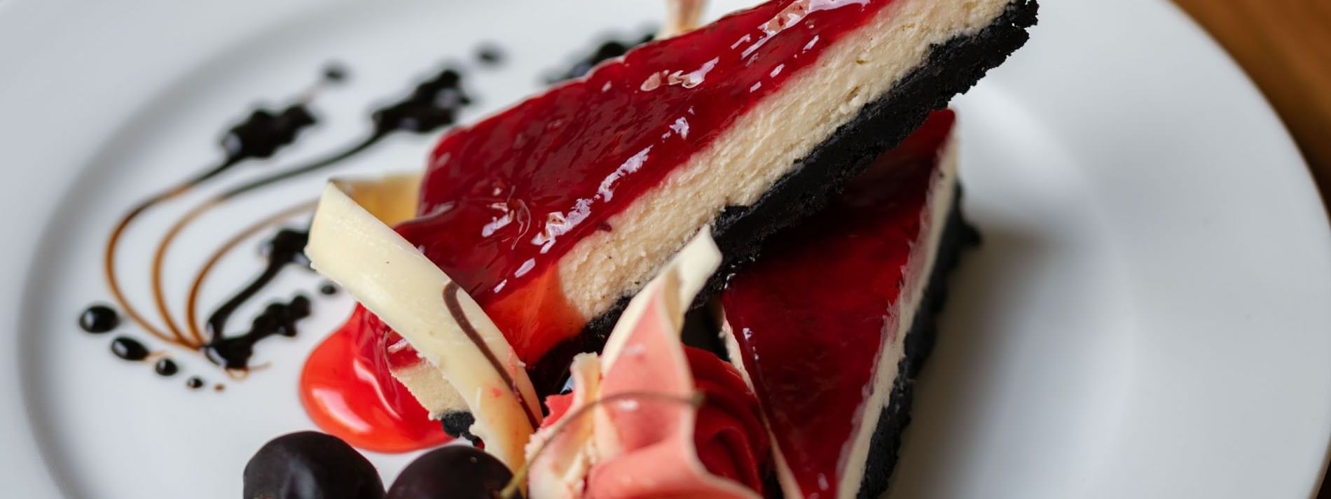 Two slices of cheesecake with a red glaze and dark crust served in the Artist Lobby Lounge at Warwick Hotel Jeddah