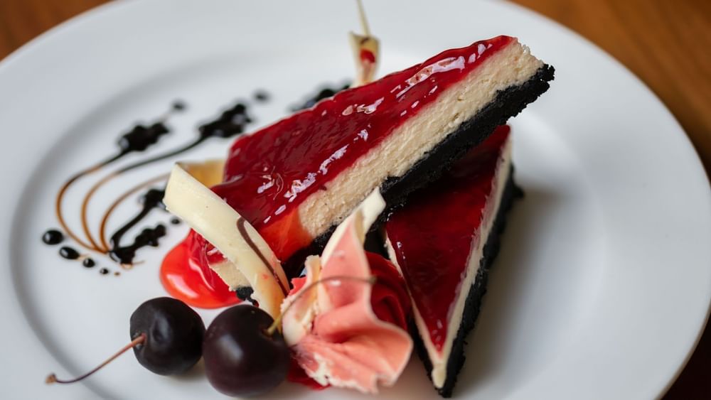 Two slices of cheesecake with a red glaze and dark crust served in the Artist Lobby Lounge at Warwick Hotel Jeddah