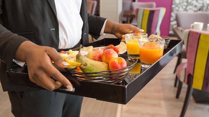 A waiter carries fancy fruit with juice at au relais saint el.
