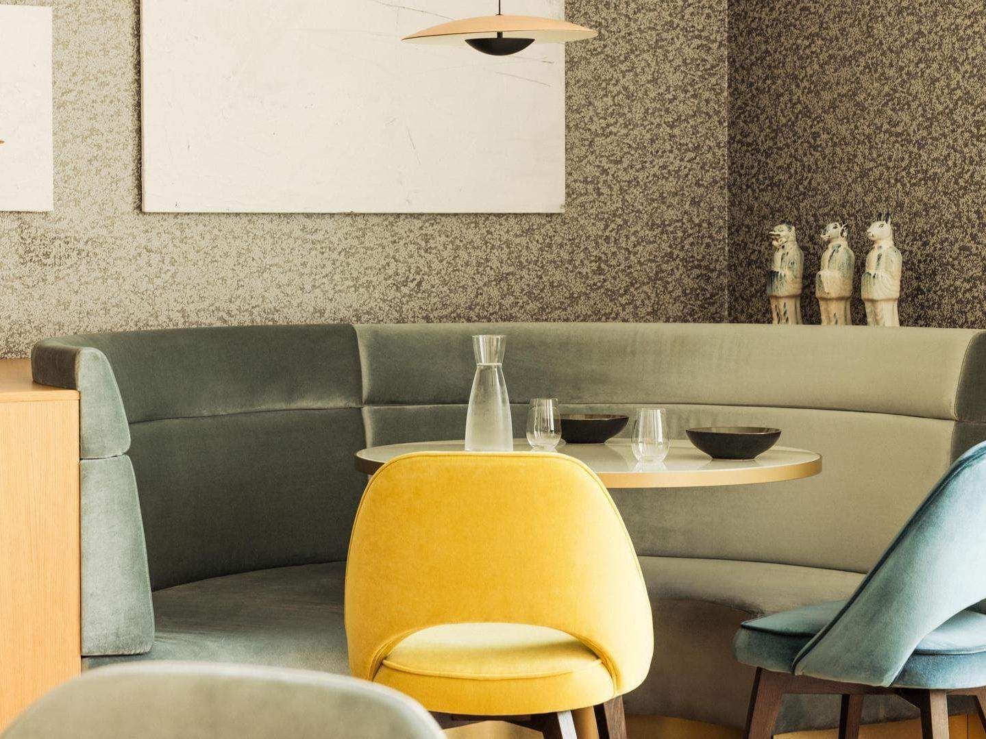 A cozy interior with a curved couch, round table, two chairs, and decorative elements.