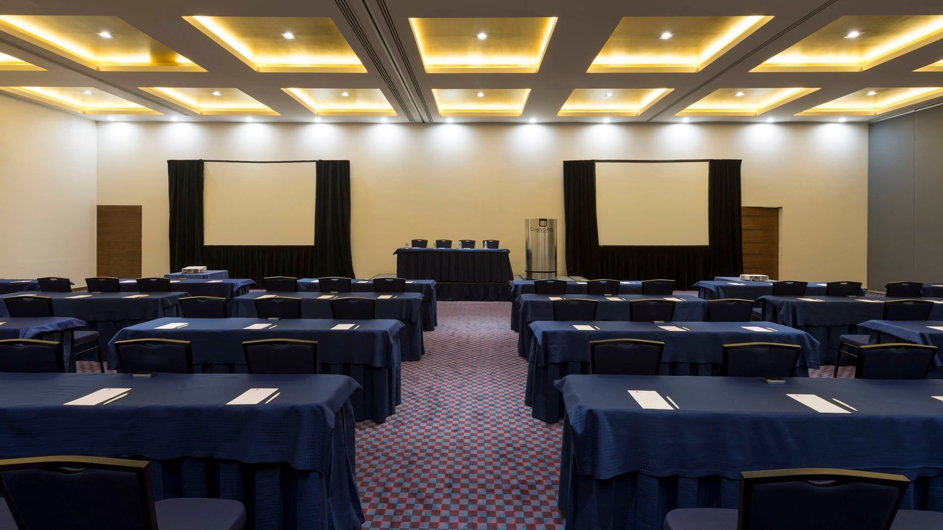 Gdl-Hmo theater-style event hall at Camino Real Pedregal Mexico, with neat rows of black chairs and gold ceiling