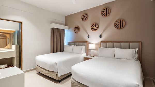 Suite De 1 Recámara Vista Frontal Al Mar featuring two beds, tan accents, and wooden wall decorations at Sunvivia Mazatlán