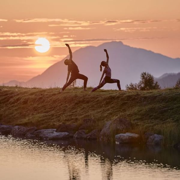 A couple doing yoga at sunrise near Falkensteiner Hotels