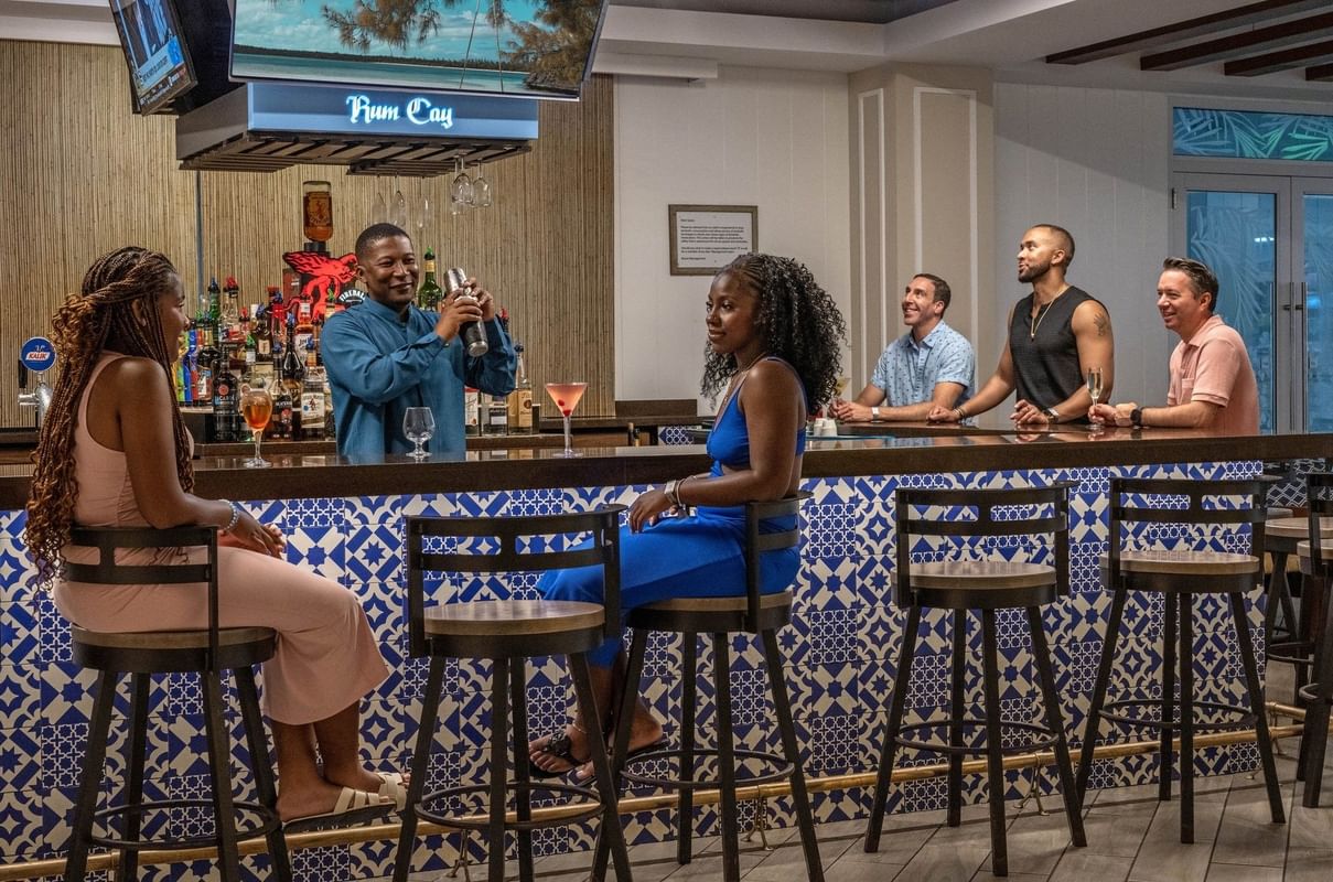Guests on high stools by a blue tiled bar in Rum Cay Lobby Bar at Warwick Paradise Island Bahamas