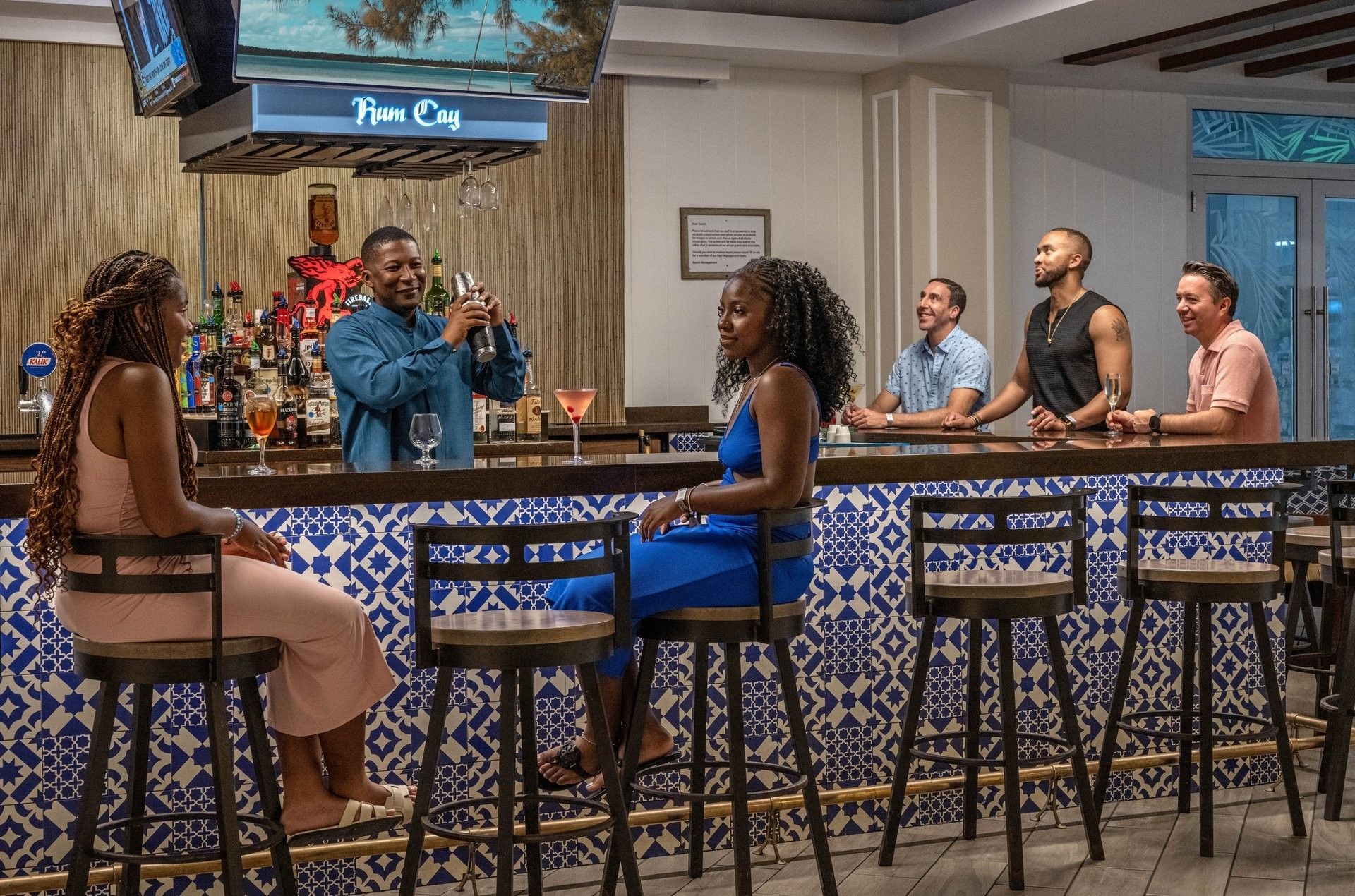 Guests on high stools by a blue tiled bar in Rum Cay Lobby Bar at Warwick Paradise Island Bahamas